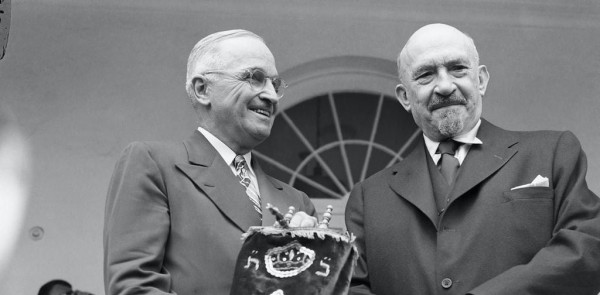 Two men in suits stand, one holding a Torah. U.S. President Harry Truman holds a Torah given to him by Chaim Weizmann, the first president of Israel, in May 1948.