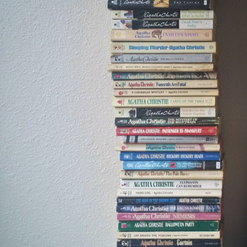 A stack of tiny vintage Agatha Christie paperback books.
